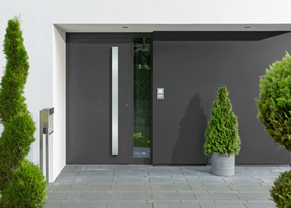 Das Bild zeigt den Eingangsbereich einer modernen Villa, im Vordergrund steht die graue und moderne Haustür. PAGA GmbH Dortmund